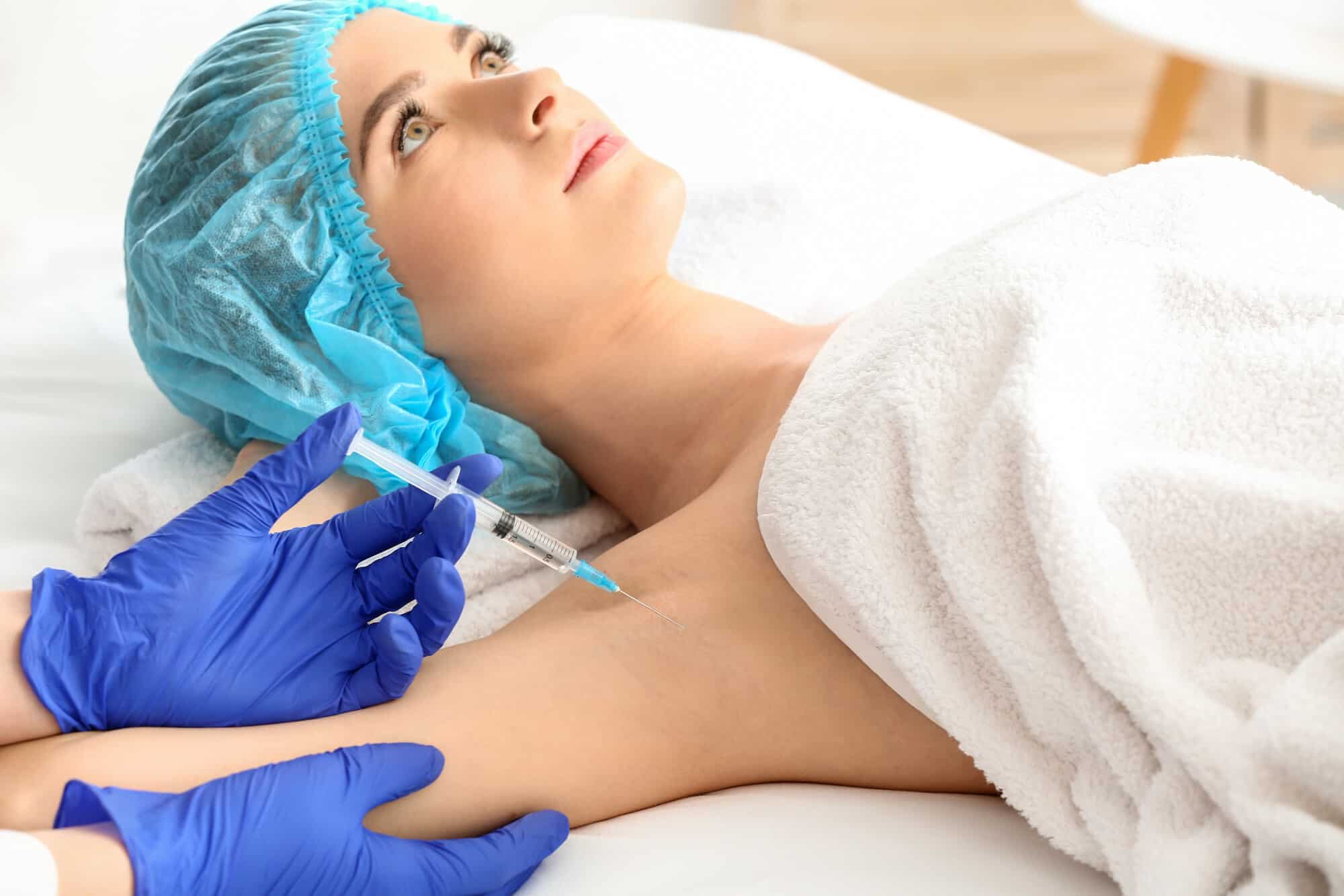 woman receiving botox injection in armpit as treatment of hyperhidrosis in beauty salon