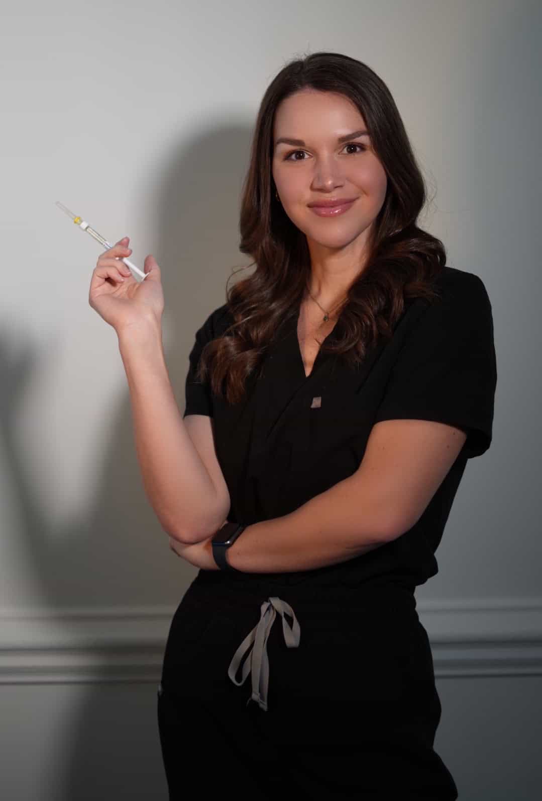 Woman holding syringe, smiling confidently.