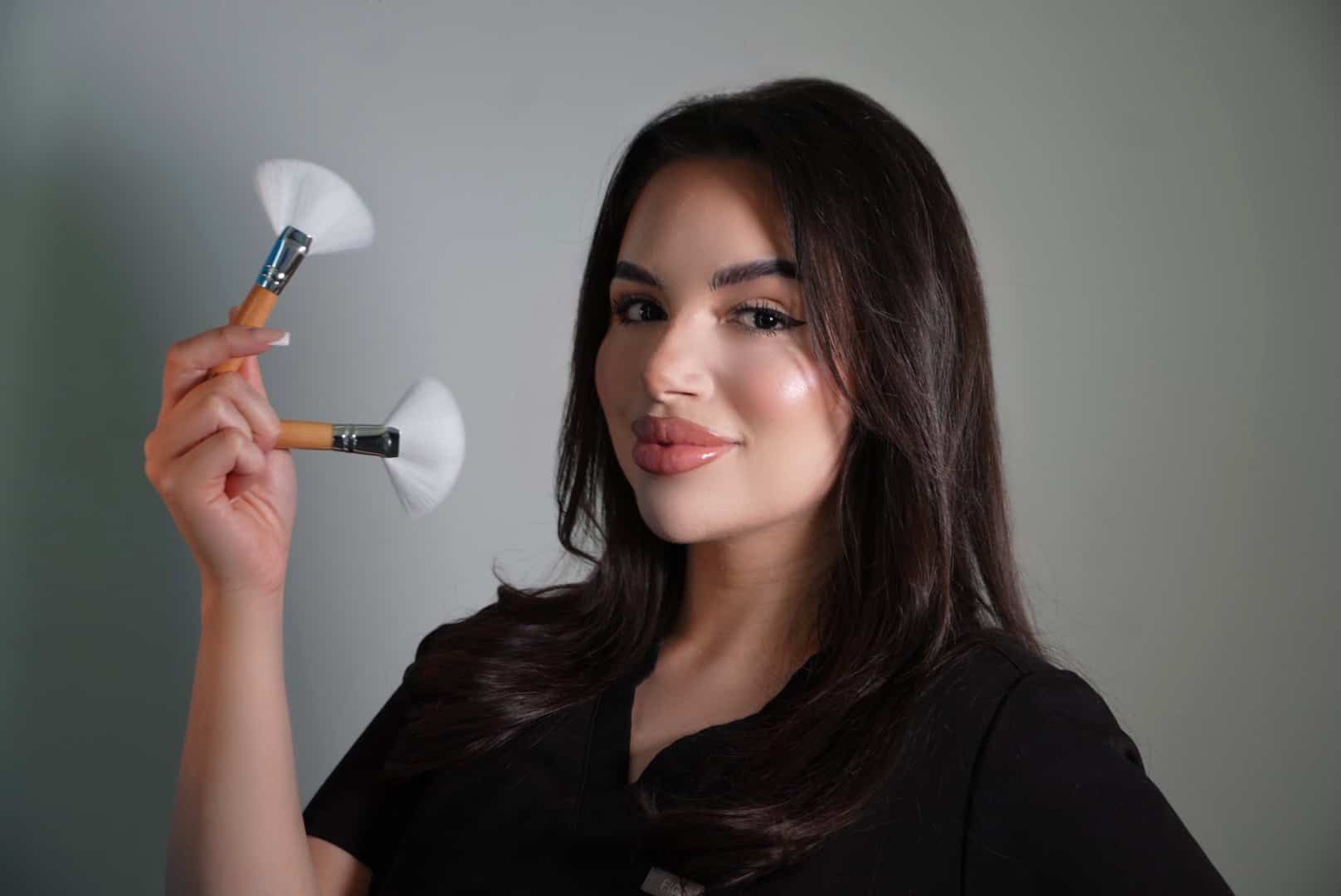 Woman holding makeup brushes, smiling