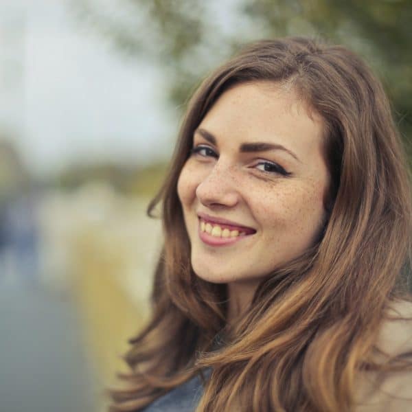 Smiling woman outdoors with blurred background.