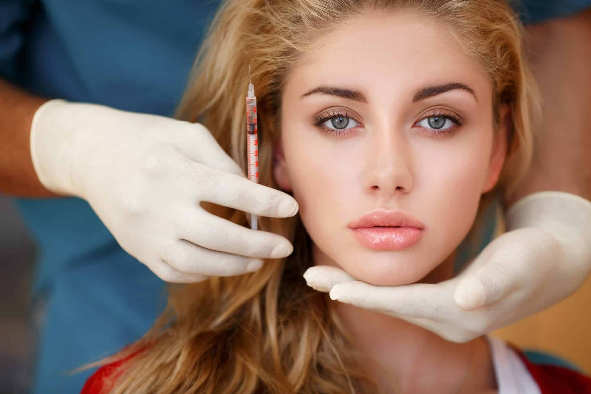 Cosmetic procedure with syringe and gloves.