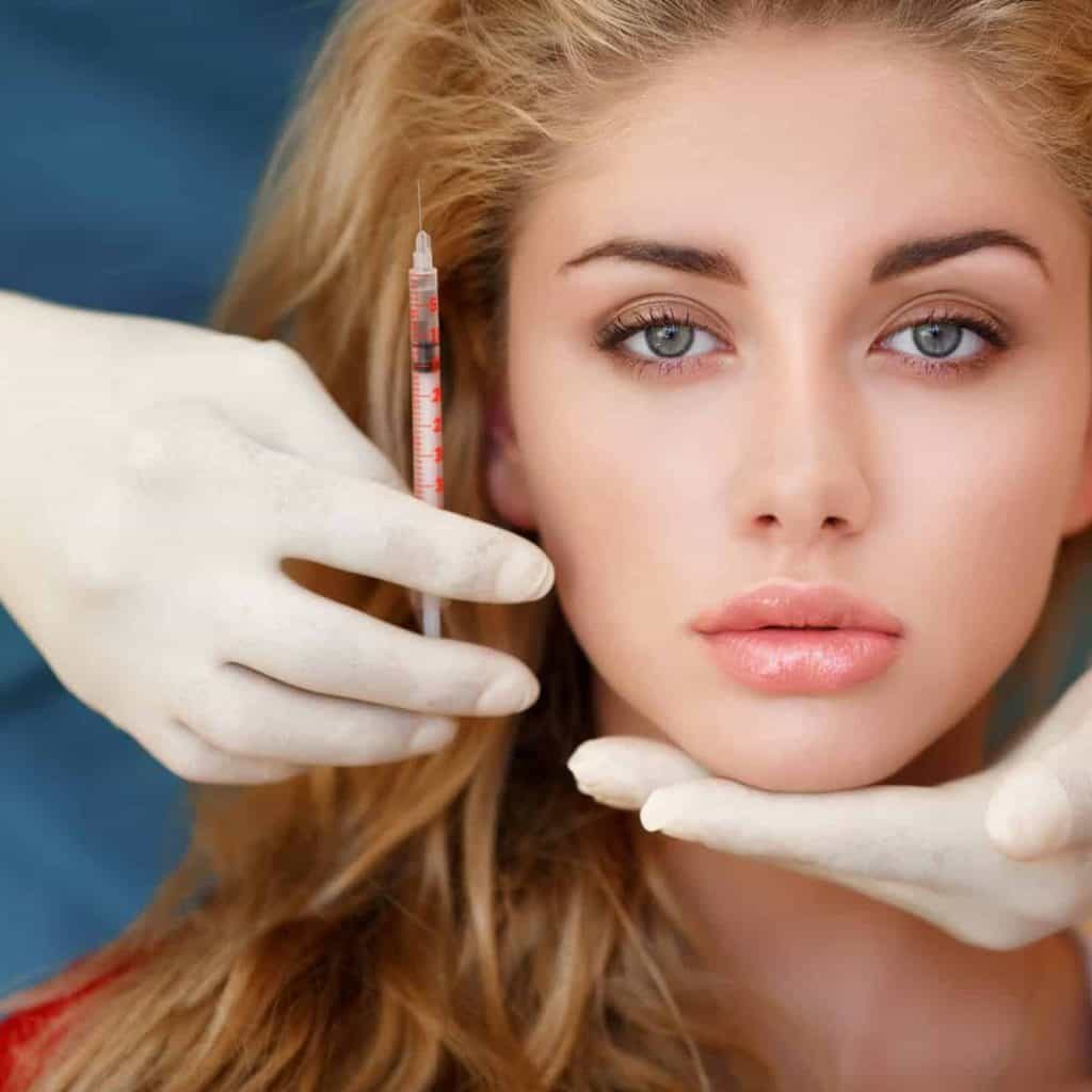 Cosmetic procedure with syringe and gloves.