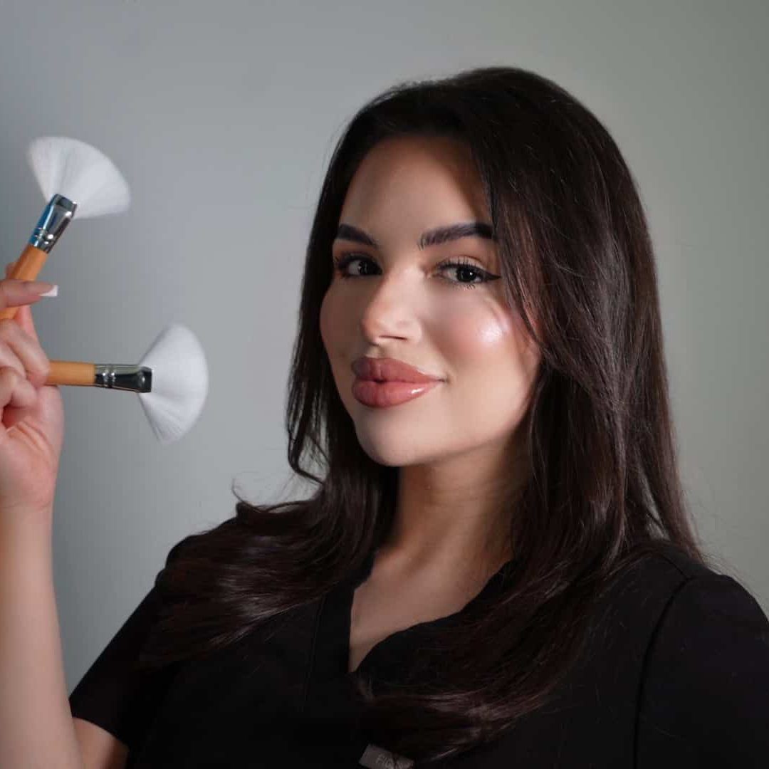 Woman holding makeup brushes, smiling