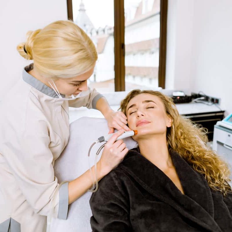 Professional young female doctor cosmetologist doing hydrafacial procedure in cosmetology clinic using hydra vacuum cleaner. Rejuvenation And Hydratation. Cosmetology.
