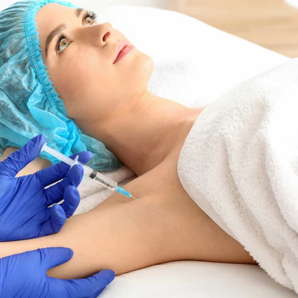 woman receiving botox injection in armpit as treatment of hyperhidrosis in beauty salon